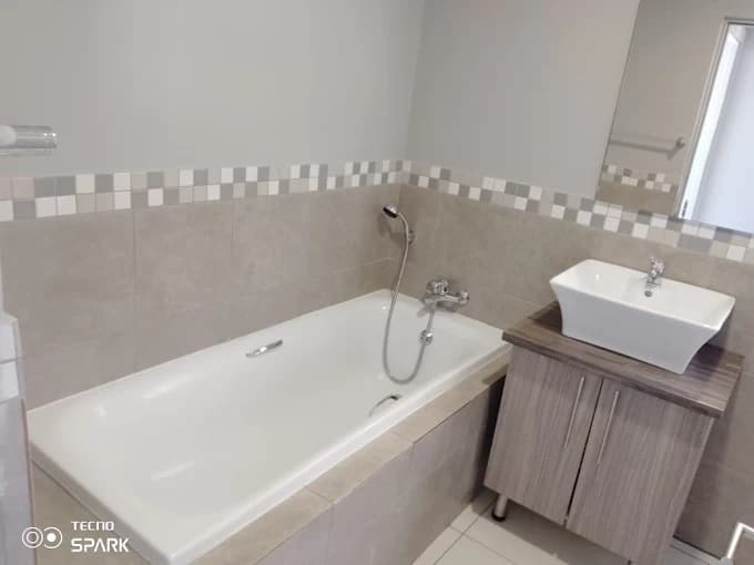 Completed bathroom with bathtub, basin, and wall tiling